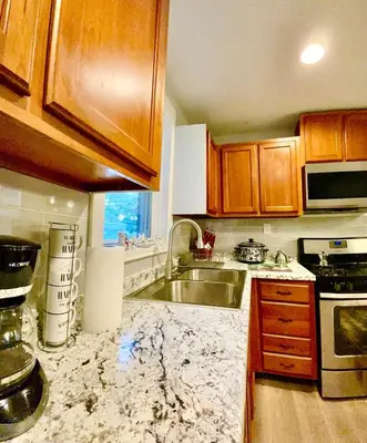 a kitchen with wooden cabinets and a sink at Very cozy 3 bedroom house close to everything in Chester