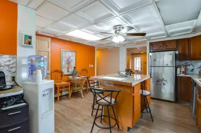 a kitchen with orange walls and an island with bar stools at Mtn-View Balcony! All-Season Apt Near Jim Thorpe in Nesquehoning