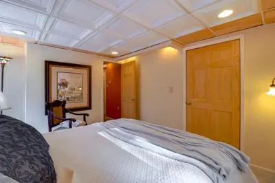 a bedroom with a white bed and a wooden door at Mtn-View Balcony! All-Season Apt Near Jim Thorpe in Nesquehoning