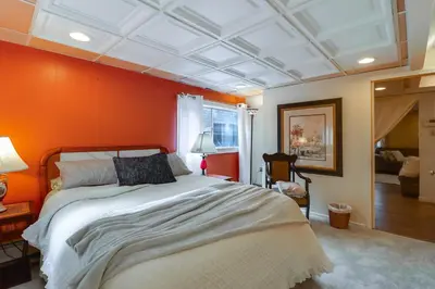a bedroom with a large bed with an orange wall at Mtn-View Balcony! All-Season Apt Near Jim Thorpe in Nesquehoning
