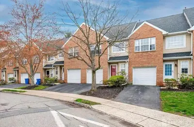 a brick house with two white garage doors at Comfortable Private Room with Bath Easy Transit in Piscataway