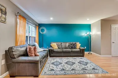 a living room with two leather couches and a blue wall at Comfortable Private Room with Bath Easy Transit in Piscataway
