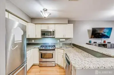 a kitchen with white cabinets and a stainless steel refrigerator at Comfortable Private Room with Bath Easy Transit in Piscataway
