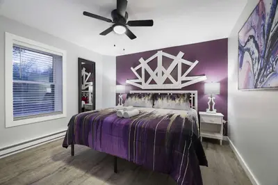 a bedroom with a purple bed with a ceiling fan at Moon Mtn Manor Sleeps 16 Karaoke Hot Tub in Albrightsville