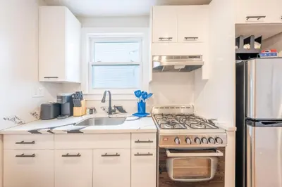 a white kitchen with a stove and a sink at Modern 2BR 8 mins to Penn Station with WiFi Laundry in Newark
