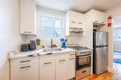 a kitchen with white cabinets and a stainless steel refrigerator at Modern 2BR 8 mins to Penn Station with WiFi Laundry in Newark