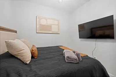 a bedroom with a bed with pillows and a flat screen tv at Cozy and Modern 3BR Apartment 5min to PATH to NYC in Jersey City