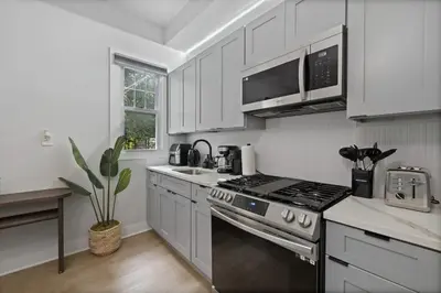 a kitchen with white cabinets and a stove top oven at Cozy and Modern 3BR Apartment 5min to PATH to NYC in Jersey City