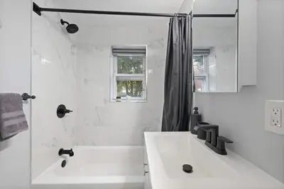 a white bathroom with a sink and a shower at Cozy and Modern 3BR Apartment 5min to PATH to NYC in Jersey City