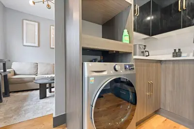 a washer and dryer in a kitchen with a living room at Modern & Cozy Studio in Jersey 20 Min to New York in Jersey City