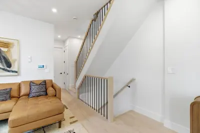 a living room with a couch and a staircase at Designer Luxury Duplex a few mintues to NYC with Skyline Views in Jersey City
