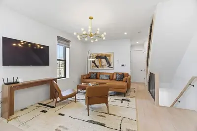 a living room with a couch and a tv on a wall at Designer Luxury Duplex a few mintues to NYC with Skyline Views in Jersey City