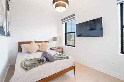 a bedroom with a bed with a tv on the wall at Designer Luxury Duplex a few mintues to NYC with Skyline Views in Jersey City