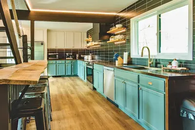 a large kitchen with blue cabinets and a window at NEW! Montview Chalet - Hot Tub, Sauna, EV, Views in East Stroudsburg