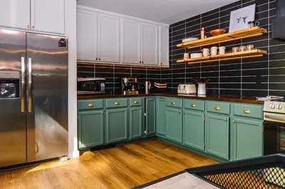 a kitchen with green cabinets and a stainless steel refrigerator at NEW! Montview Chalet - Hot Tub, Sauna, EV, Views in East Stroudsburg