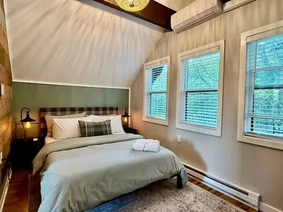 a bedroom with a bed and two windows at NEW! Montview Chalet - Hot Tub, Sauna, EV, Views in East Stroudsburg