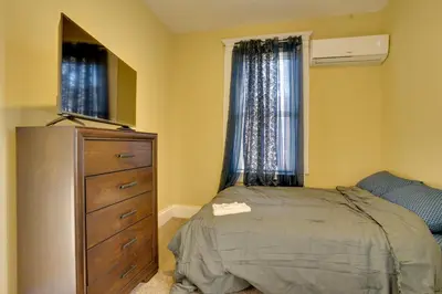 a bedroom with a bed and a dresser and windows at Easy City Commuting! Walkable Newark Duplex in Newark