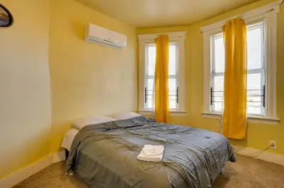 a bedroom with a bed with yellow walls and windows at 2 Mi to Rutgers University! Urban Hub Near Parks in Newark