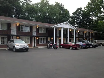 a building with cars parked in a parking lot at Coachman Motor Lodge in Elmira