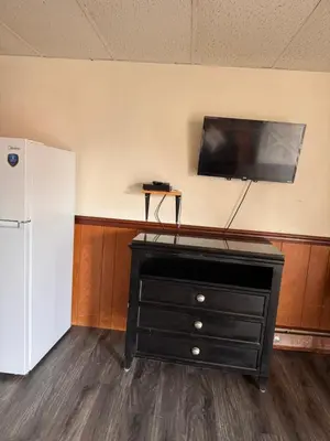 a black dresser with a flat screen tv on a wall at Coachman Motor Lodge in Elmira