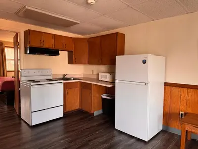 a kitchen with a white refrigerator and wooden cabinets at Coachman Motor Lodge in Elmira