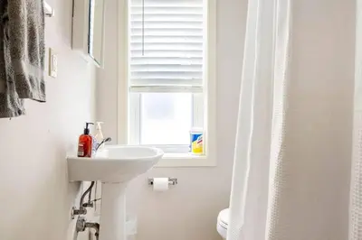 a white bathroom with a sink and a window at Family Friendly Home in Trolley Square in Wilmington