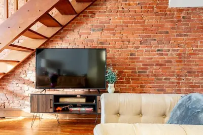 a living room with a television in a brick wall at Family Friendly Home in Trolley Square in Wilmington