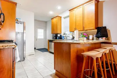 a kitchen with wooden cabinets and a bar with stools at Family Friendly Home in Trolley Square in Wilmington
