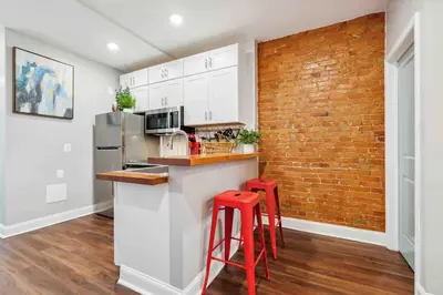 a kitchen with red stools and a brick wall at 4BR Near HUP, CHOP, UPENN Free Parking 30 Days in Philadelphia