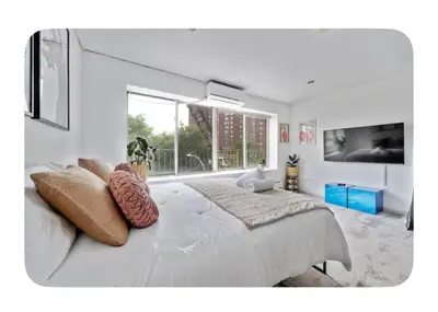 a white bedroom with a large bed and a large window at Bright and spacious apt, W&D in unit - Monthly in New York