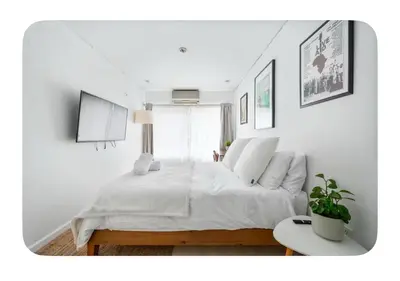 a white bedroom with a bed and a table at Bright and spacious apt, W&D in unit - Monthly in New York