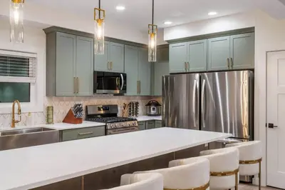 a kitchen with green cabinets and a stainless steel refrigerator at 9 BR,34 Sleeps Skiing Lake Sauna Hottub Kayaks in Lake Harmony