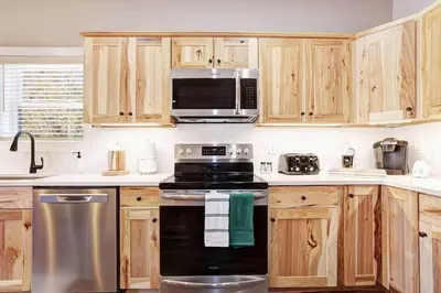a kitchen with wooden cabinets and a black stove top oven at New Luxe! 9BR,7BA, Elevator, Sleeps 30, EV Charger in Lake Harmony