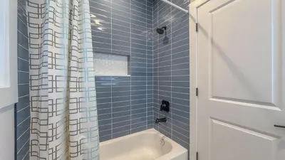 a blue tiled bathroom with a tub and a shower curtain at Pristine Pad, Sleep 12, Free parking, 3BRs, 20 PERCENT OFF in East Newark