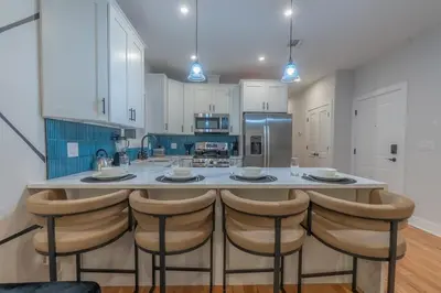 a kitchen with white cabinets and a island with bar stools at Pristine Pad, Sleep 12, Free parking, 3BRs, 20 PERCENT OFF in East Newark