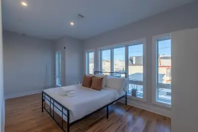 a white bed in a room with large windows at Pristine House, Sleep 21, Park 2 cars FREE, 20 PERCENT OFF in East Newark