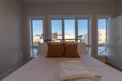 a bedroom with a large white bed with windows at Pristine House, Sleep 21, Park 2 cars FREE, 20 PERCENT OFF in East Newark