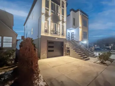 a large white building with a garage and stairs at Pristine House, Sleep 21, Park 2 cars FREE, 20 PERCENT OFF in East Newark