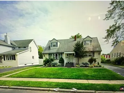 a white house with a green lawn at House For Rent Near MetLife Stadium in Hasbrouck Heights