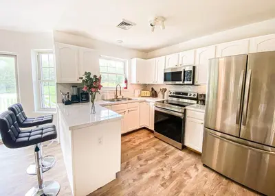 a kitchen with white cabinets and a stainless steel refrigerator at PrivatePool|Hot tub|Sauna|HomeTheater|Backyard in Long Pond