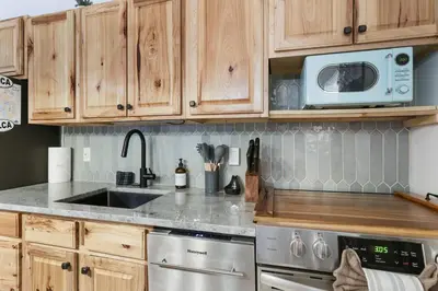 a kitchen with wooden cabinets and a sink and a microwave at Evergreen Escape Hot Tub Firepit Resort Pool in Thornhurst