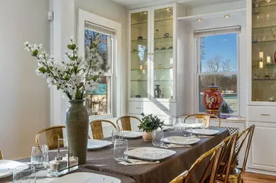 a dining room with a table with chairs and a vase with flowers at 5BR Home Minutes to NYC and FIFA 2026 Sleeps 16 in Teaneck