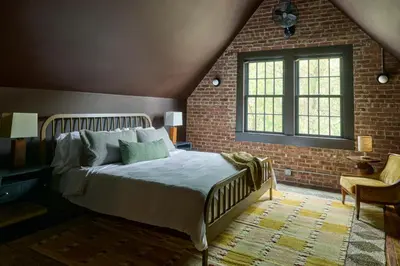 a bedroom with a bed and a brick wall at Eleanor Inn - Suite Amelia in Warwick