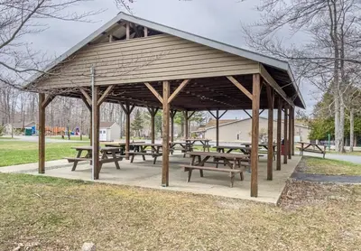 a picnic shelter with picnic tables in a park at Cozy Pocono Retreat in Tobyhanna