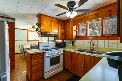 a kitchen with wooden cabinets and a white stove top oven at Year-Round Fun on Lake Sheridan! Home with Patio