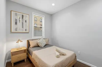 a small bedroom with a bed and a night stand at Spacious 3BR 2BA Apt with Private Parking Walk to PATH in Jersey City