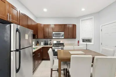 a kitchen with a table and a refrigerator at Spacious 3BR 2BA Apt with Private Parking Walk to PATH in Jersey City