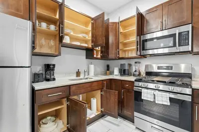 a kitchen with wooden cabinets and a stove top oven at Spacious 3BR 2BA Apt with Private Parking Walk to PATH in Jersey City