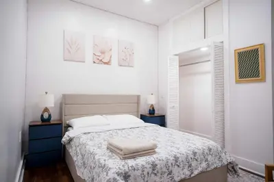 a white bedroom with a bed and two night stands at Stylish & Comfortable City Stay in West New York