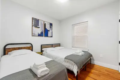 two beds in a room with white walls and a window at Premier 3BR-5BD-3Bath Retreat with NYC Access in Jersey City